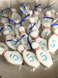 decorated cookies in the shape of bowling pins with blue and red ribbons tied around them