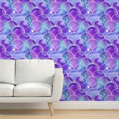 a white couch sitting in front of a wall with purple and blue scales on it