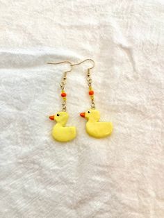 a pair of yellow rubber ducks dangling from gold earwires on a white sheet