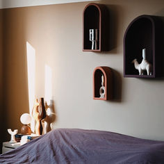 three shelves on the wall above a bed with a purple bedspread and pillows