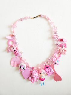 A unique necklace made out of a variety of different vintage to modern toys. Handcrafted from real toys, this one of a kind necklace is sure to impress. Fun Pink Jewelry With Lobster Clasp, Fun Pink Charm Necklace, Playful Handmade Charm Necklaces For Birthday, Playful Handmade Charm Necklace For Birthday, Whimsical Pink Pendant Necklace, Unique Handmade Necklaces For Birthday, Unique Handmade Birthday Necklaces, Playful Pink Charm Necklaces For Jewelry Makers, Whimsical Charms Necklace For Birthday