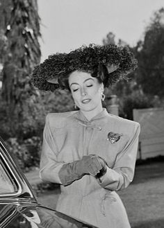 a woman with a hat on her head getting out of a car