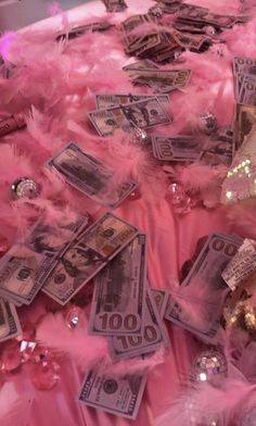 money and pink feathers are scattered on the bed