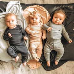 three babies laying on top of a black blanket