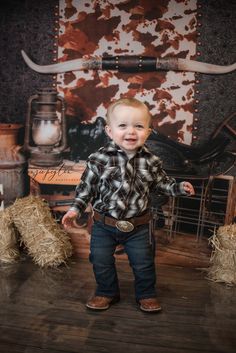 a little boy standing in front of hay bales and smiling at the camera with his arms out