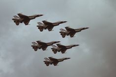 four fighter jets flying in formation against a cloudy sky