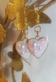 These earrings are a fun, cute addition to any outfit! They were made using a metal open bezel, UV resin, and decorate iridescent half pearls. -Each item is handmade -Any resin may contain small bubbles, which is normal for this type of medium -All sales are final, no returns, refunds, or exchanges. But if you have any questions regarding your order feel free to message me! Pearl Heart-shaped Earrings For Gifts, White Heart Drop Earrings For Jewelry Making, Heart-shaped Pearl Earrings Gift, Heart-shaped Pearl Earrings For Gifts, Handmade Enamel Earrings For Party, Trendy Iridescent Jewelry For Gifts, Whimsical White Resin Jewelry, Pearl Drop Heart Earrings Gift, Cute Handmade Metal Jewelry