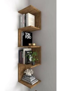 three wooden shelves with books and magazines on them in a corner next to a white wall