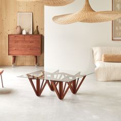 a living room filled with furniture and lamps hanging from the ceiling over it's glass top table