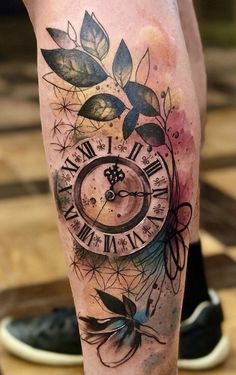 a man's leg with a clock tattoo on it and flowers around the clock