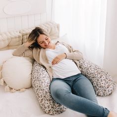 a pregnant woman laying on her stomach on a pillow in the middle of a bed