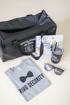 a bag with sunglasses, t - shirt and other items in it sitting on a table