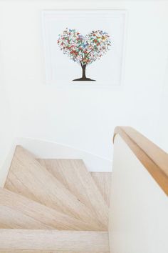 a tree with colorful leaves on it in the corner of a room next to stairs