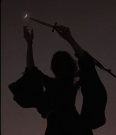 the silhouette of two people holding up their arms in the air, with one person reaching for the moon