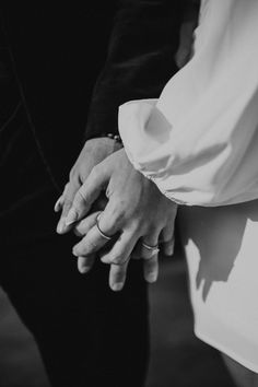 the bride and groom hold hands as they stand next to each other in black and white