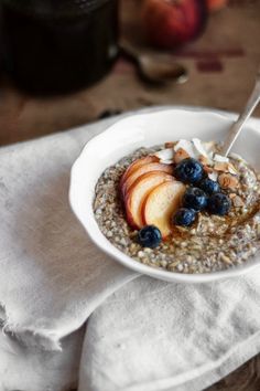 a bowl of oatmeal with apples and blueberries in it on a napkin