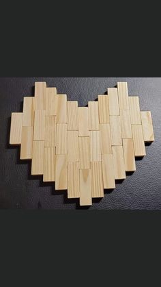 a heart made out of wooden planks on a black surface with one piece missing