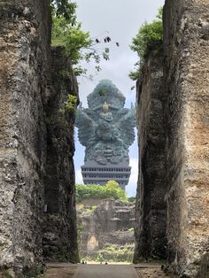 the entrance to an ancient city with a giant statue in the middle and trees growing out of it