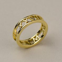 a yellow gold ring with roman numerals on the outside and an engraved design on the inside