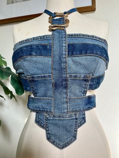 a mannequin wearing a denim top with an open back and metal buckles