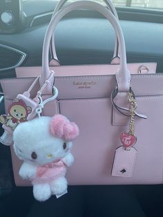 a pink hello kitty purse and keychain in a car