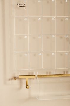 a white wall with a calendar on it and a gold bar in front of it