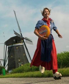 a woman is holding a basketball in front of windmills