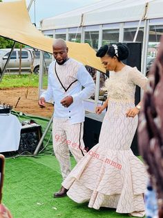 a man and woman are walking on the green carpeted area at an outdoor event