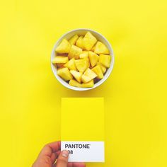 a person holding a business card in front of a bowl of pineapples on a yellow background