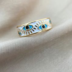 Introducing the Evil Eye Ring by Asana, a magical and stylish statement piece that is perfect for any outfit. This eye ring is made from high-quality metals with a beautiful gold finish. The center stone is an eye-shaped piece of enamel that is said to ward off evil spirits. This ring is adjustable to fit any finger size and makes a great gift for anyone who loves unique jewelry & needs some spiritual protection.      	Size: Adjustable - 6,7,8,9  	Free Shipping 2 Days  	Authentic Enamel  	Brand: Handmade Gold Enamel Ring, White Evil Eye Ring Jewelry, White Evil Eye Ring, Gold Evil Eye Open Ring, Gold Open Ring With Evil Eye, Gold Open Ring With Evil Eye Detail, Spiritual Rings, Eye Rings, Ward Off Evil Spirits