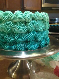 a blue and green cake sitting on top of a metal platter in a kitchen