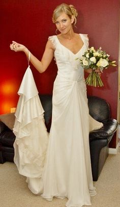 a woman in a white wedding dress holding a bouquet and pointing to the side with her right hand