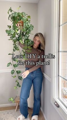 a woman leaning against a wall holding a potted plant with the words let's diy a trellis for this plant