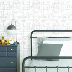 a black and white bedroom with wallpaper that has lines drawn on it, along with a gold alarm clock