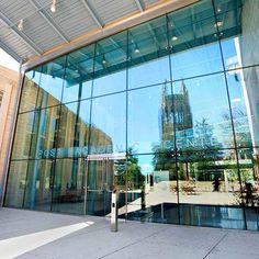 a large glass building with a clock tower reflected in it