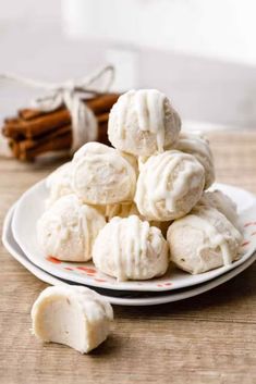 a white plate topped with cookies covered in icing next to cinnamon sticks on a table