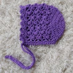 a purple crocheted hat laying on top of a white blanket