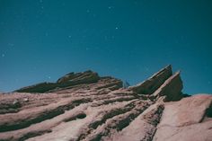 a person standing on top of a rocky mountain under a night sky filled with stars