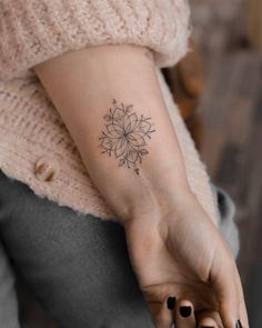 a woman's arm with a flower tattoo on the left side of her wrist