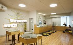 the inside of a store with wooden floors and tables on each side, people are sitting in the background