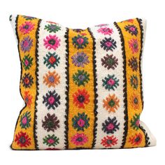 a yellow and black pillow with multicolored flowers on the front, sitting on a white background