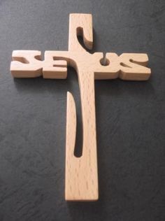 a wooden cross with the word jesus carved into it's sides on a black surface