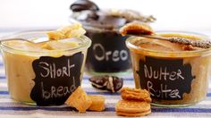 three cups of peanut butter and crackers are sitting on a striped tablecloth with chalk writing