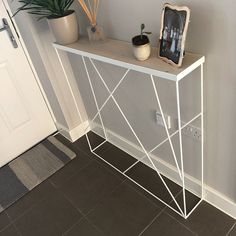 a white shelf sitting next to a door and potted plant on top of it