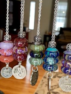 several different colored glass beads hanging from a metal chain on a wooden table in a living room