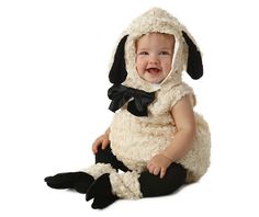 a baby wearing a sheep costume sitting on the ground with its legs crossed and mouth open