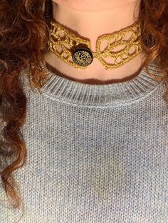 a close up of a person wearing a sweater with a gold chain around their neck