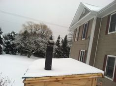 a snow covered roof with a mailbox in the foreground and a house in the background