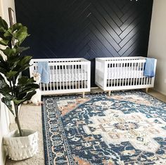 two white cribs in front of a black wall