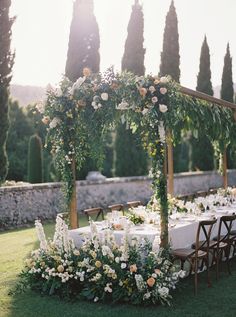 an outdoor table with flowers and greenery is set up for a wedding reception in the sun